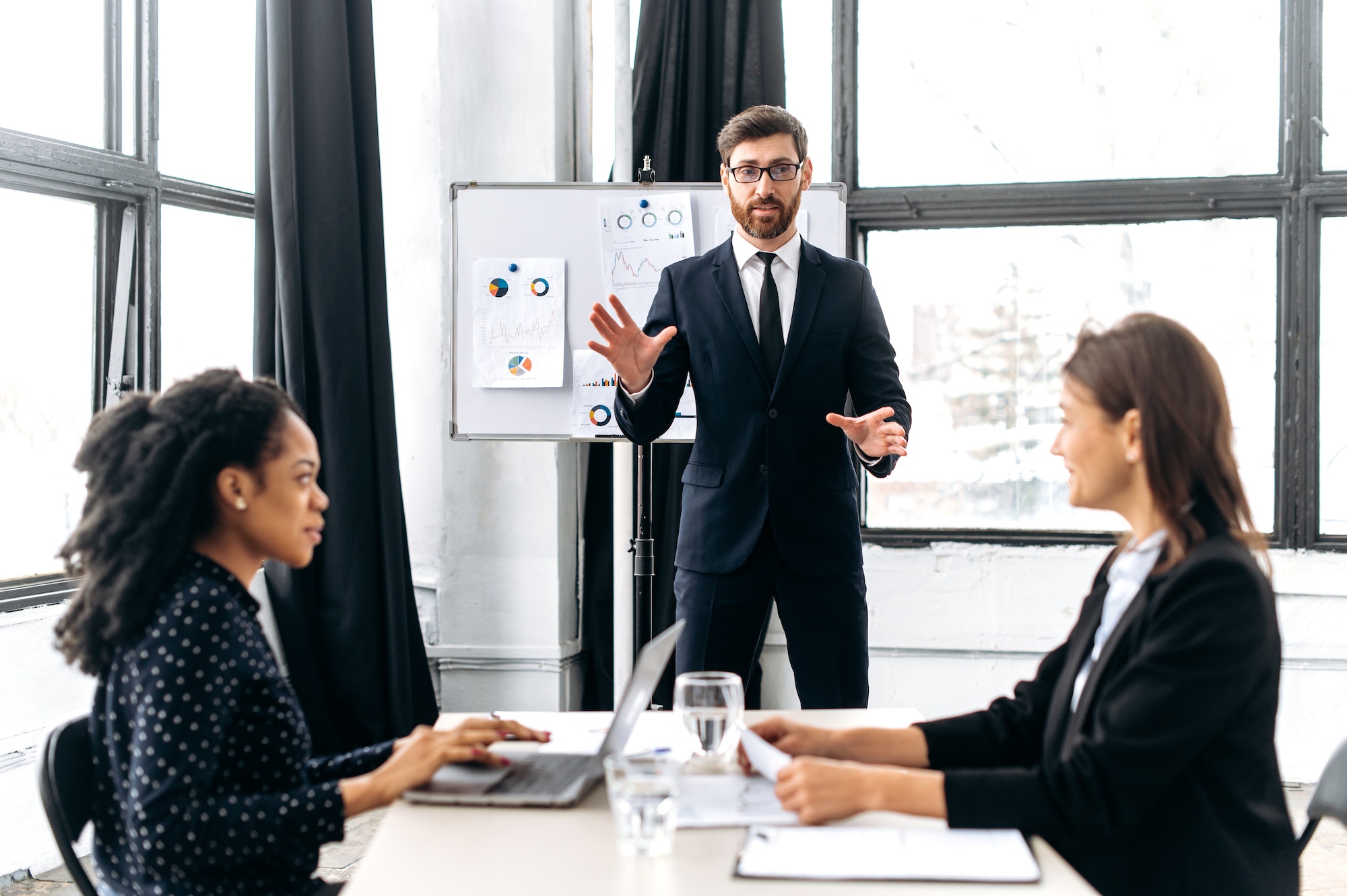 Elegant Caucasian intelligent male boss, holding group brainstorm with female colleagues, discussing